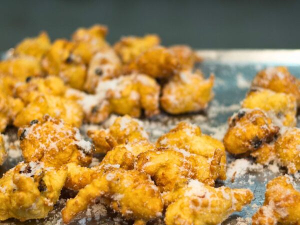 fritelle covered in sugar on a tray