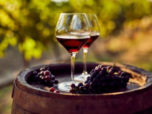 red wine in glasses on top of wine barrel