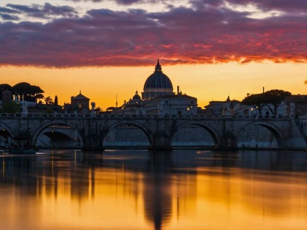 sunset over the tiber river in rome with st peter's basilica in the distance